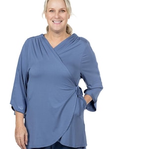 Puede incluir: Un conjunto de pijama azul de dos piezas con una parte superior de envoltura y pantalones de pierna ancha. La parte superior tiene un cuello en V y un lazo en la cintura. Los pantalones tienen un ajuste holgado.