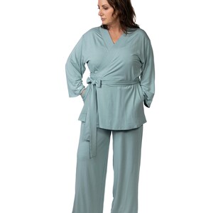 May include: A light blue, long-sleeved, wrap-style top with a matching pair of wide-leg pants. The top has a V-neck and a tie belt at the waist. The pants have pockets on the sides.