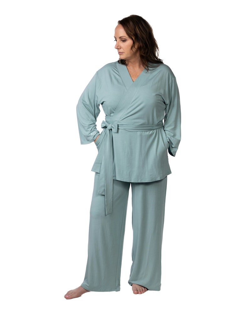 May include: A light blue, long-sleeved, wrap-style top with a matching pair of wide-leg pants. The top has a V-neck and a tie belt at the waist. The pants have pockets on the sides.