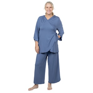 Puede incluir: Una blusa azul de manga larga, estilo envolvente, con un lazo en la cintura y pantalones anchos a juego. El conjunto está hecho de una tela suave y cómoda.