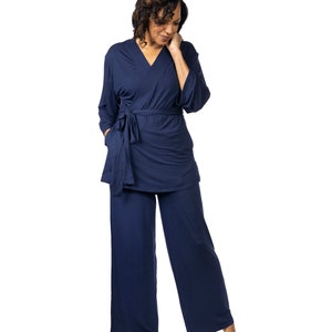 May include: A navy blue pajama set with a long-sleeved top and wide-leg pants. The top has a wrap style and a tie at the waist.