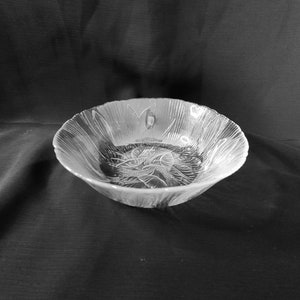 May include: A clear glass bowl with a decorative floral pattern. The bowl is empty and sitting on a black surface.