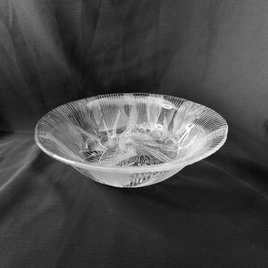 May include: A clear glass bowl with a decorative, textured design. The bowl is empty and has a slightly rounded shape.