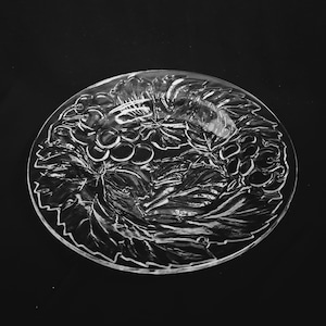 May include: A clear glass serving plate with an etched design of grapes and leaves.