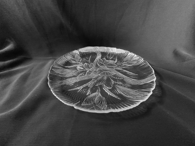 May include: A clear glass serving platter with a decorative floral design. The platter has a scalloped edge and is perfect for serving appetizers, desserts, or other snacks.