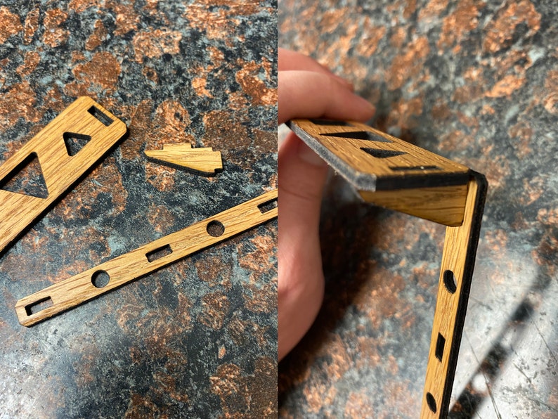 May include: A wooden craft kit with various pieces, including a long rectangular piece with cutouts, a smaller triangular piece, and a larger piece with a black edge. The pieces are made of light brown wood with a natural grain.