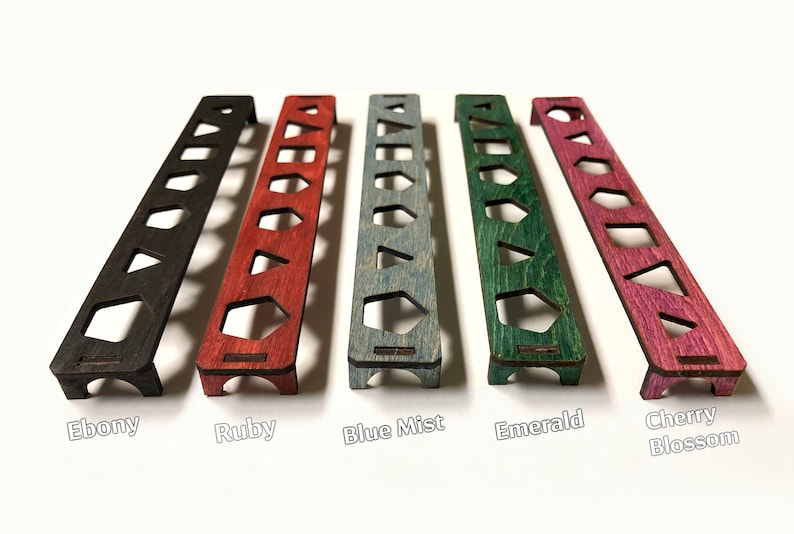 May include: Five wooden dice trays in different colours: ebony, ruby, blue mist, emerald, and cherry blossom. Each tray has seven slots for dice.