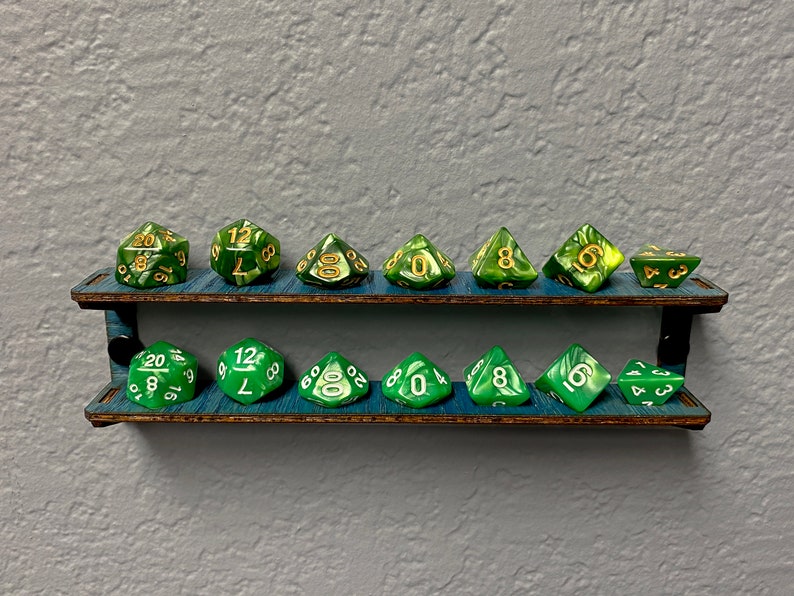 May include: A two-tiered wooden shelf with a dark brown stain holds a set of 12 green and gold dice. The dice are arranged in two rows of six, with each row containing a different set of numbers.