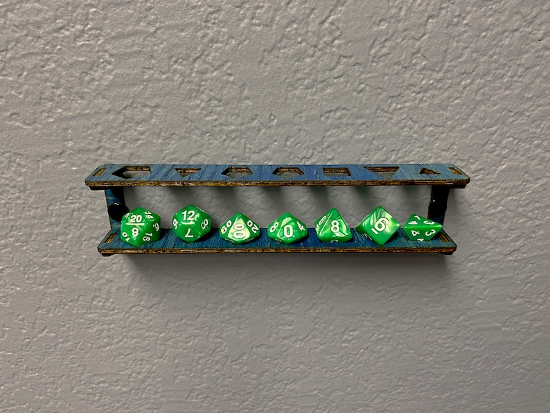 May include: A wooden wall-mounted dice holder with seven slots, each holding a green and white polyhedral die. The dice are numbered 20, 12, 8, 0, 8, 6, and 4.