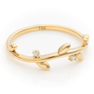 May include: A delicate gold ring with a twig design and small diamonds. The ring is marked "14K" on the inside.