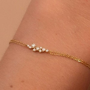 May include: A delicate gold chain bracelet with a cluster of small diamonds set in a curved line.