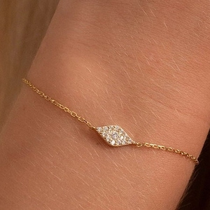 May include: A delicate gold chain bracelet featuring a small diamond-shaped charm set with tiny diamonds.