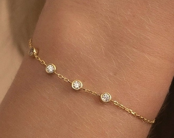 May include: A delicate gold chain bracelet with five small round clear stones.
