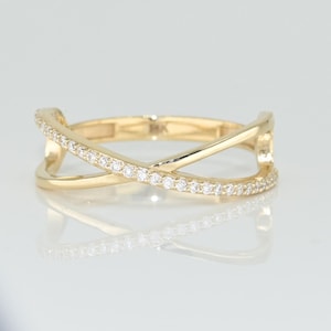 May include: A gold ring with a criss-cross design and a row of small diamonds around the band.