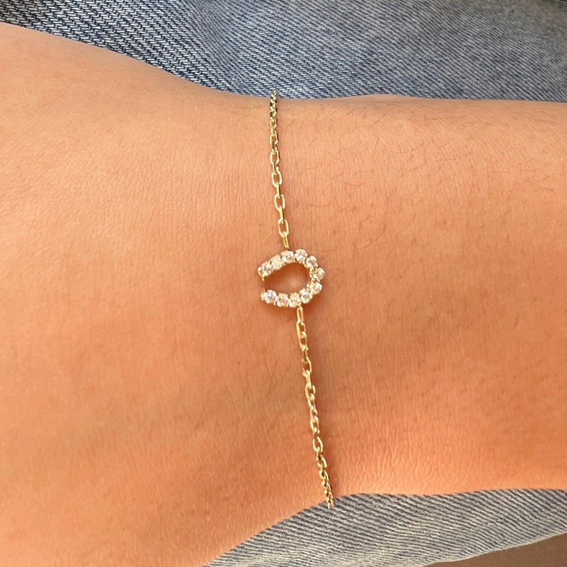 May include: A gold chain bracelet with a horseshoe charm set with small clear stones.