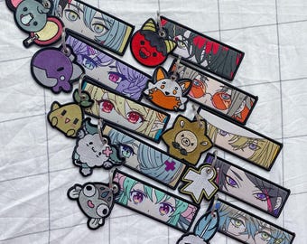 Może przedstawiać: Zestaw 10 kolorowych breloków z postaciami z anime. Każdy brelok jest wykonany z tkaniny i ma inny wzór. Breloki idealnie nadają się do dodania odrobiny osobowości do kluczy lub torebki.