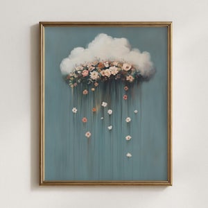 May include: A framed art print featuring a cloud with a floral arrangement and falling flowers. The artwork has a teal background and a gold frame. The flowers are in shades of pink, peach, and white.