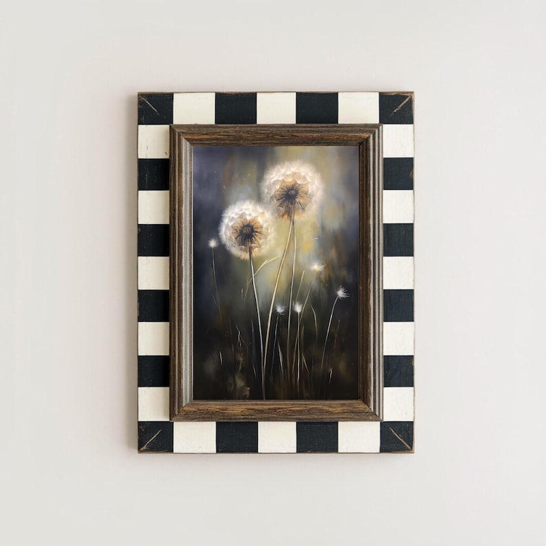 May include: A framed painting of dandelions. The artwork features two large, fluffy dandelion seed heads in the center, with smaller ones in the background. The frame is a combination of a dark wood inner frame and a black and white checkered outer frame.