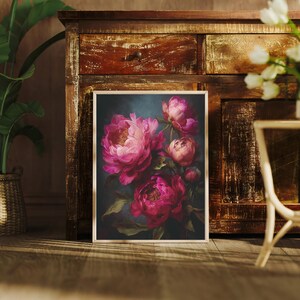 May include: A framed floral print featuring vibrant pink peonies against a dark teal background. The artwork showcases the flowers in full bloom, with detailed petals and green foliage. The print is displayed on a wooden floor, leaning against a rustic wooden cabinet.