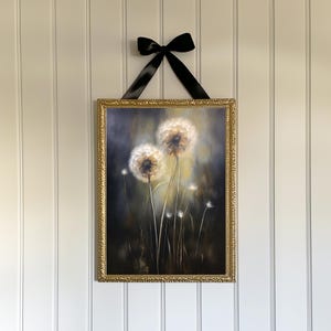 May include: A framed artwork featuring a painting of dandelions. The painting is in a gold ornate frame and is suspended by a black ribbon. The dandelions are white and fluffy against a dark background.