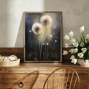 May include: A framed artwork featuring a close-up of dandelions. The painting showcases two large, fluffy dandelion seed heads with a soft, glowing light. The background is a dark, moody blend of greens and blues, with hints of yellow.