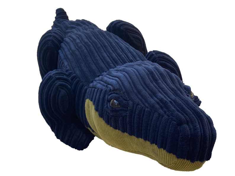 Op de afbeelding: Een pluche blauwe alligator speelgoed met een gele buik en zwarte ogen. De alligator is gemaakt van een zachte, textuurrijke stof.