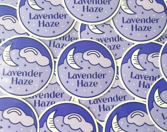 May include: A collection of round stickers with a purple and white design. Each sticker features the text "Lavender Haze" in a stylized font, along with a crescent moon, clouds, and stars. The stickers are arranged in a close-up, overlapping pattern.