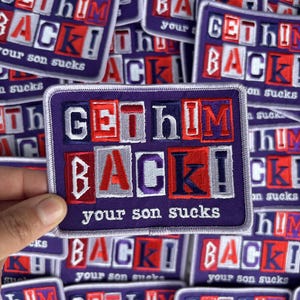 May include: A rectangular embroidered patch with a purple background featuring the text GET HIM BACK! in a ransom note style with red, white, and blue letters, and the phrase your son sucks in white text underneath on a purple border.