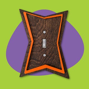 May include: A wooden light switch cover with a unique starburst design. The cover is stained a dark brown with an orange border. The light switch is silver. The background is a combination of purple and green.