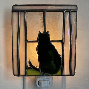Stained glass night light featuring a cat silhouette in a window is a charming and decorative piece that celebrates the love for cats.
