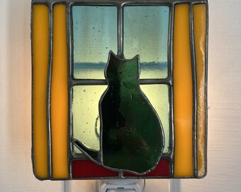 Stained glass night light featuring a cat silhouette in a window is a charming and decorative piece that celebrates the love for cats.