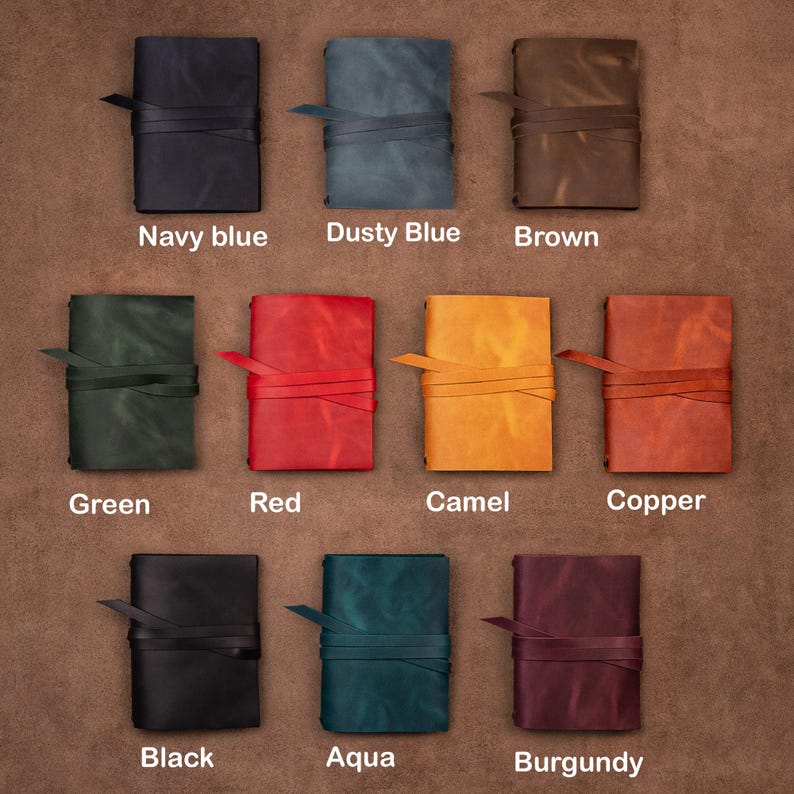 May include: Twelve leather-bound journals in various colors, including navy blue, dusty blue, brown, green, red, camel, copper, black, aqua, and burgundy. Each journal has a leather strap closure.