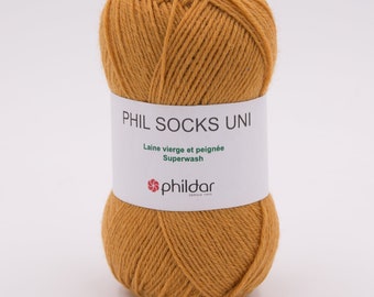 May include: A ball of mustard yellow yarn labeled "Phil Socks Uni" with the text "Laine vierge et peignée Superwash" and the logo "Phildar" in green and red.