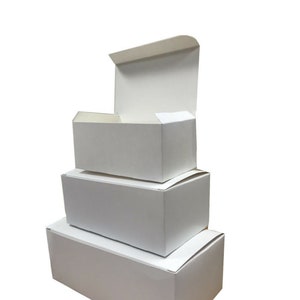 May include: A set of four white cardboard boxes stacked on top of each other. The boxes are all different sizes, with the largest box at the bottom and the smallest box at the top. The boxes are all closed, and the top box is slightly open.