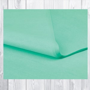 May include: A sheet of light green tissue paper folded in half. The paper is smooth and has a subtle sheen.