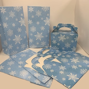 May include: A set of blue and white snowflake-patterned party favour bags and boxes. The set includes two large bags, one small box with a handle, and several smaller flat bags.