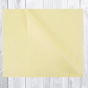 May include: A pale yellow sheet of paper with a slight fold in the centre.