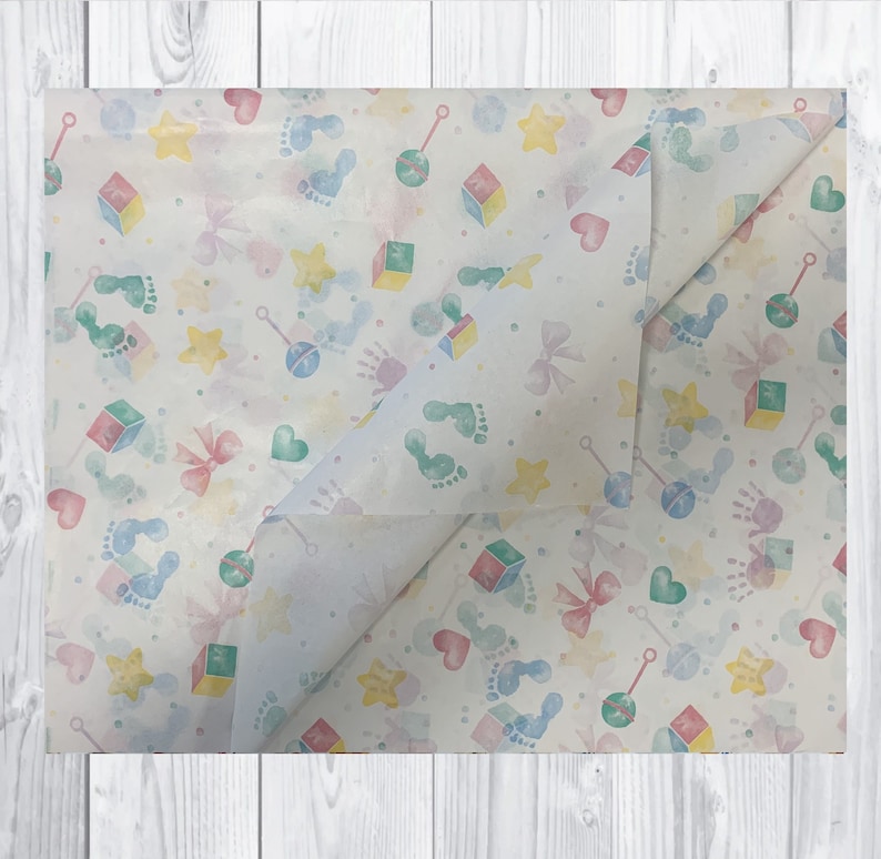May include: White tissue paper with a repeating pattern of baby footprints, stars, bows, rattles, and blocks in shades of blue, green, yellow, and pink.