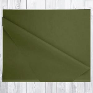 May include: Olive green tissue paper with a folded corner, set against a white wood grain background. The paper has a matte finish and a slight sheen. Suitable for gift wrapping or crafts.