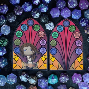 Puede incluir: Dos paneles de vitrales con un esquema de color rojo, naranja y amarillo. Cada panel presenta una figura femenina estilizada con un gato, rodeada de formas geom&eacute;tricas y s&iacute;mbolos. Los paneles est&aacute;n enmarcados en madera oscura.