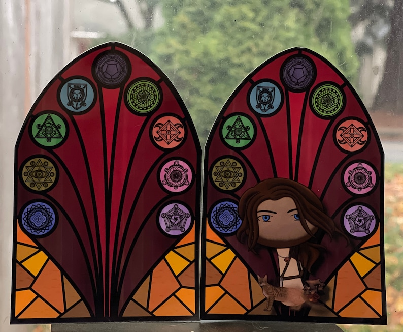 Puede incluir: Un dise&ntilde;o de vitral con un patr&oacute;n geom&eacute;trico colorido y un personaje con cabello largo y casta&ntilde;o y un gato. El dise&ntilde;o presenta un patr&oacute;n repetitivo de c&iacute;rculos y tri&aacute;ngulos con una figura central.