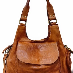 Può includere: Borsa a tracolla in pelle marrone con tasca frontale con patta. La borsa ha un manico superiore e una tracolla staccabile. La pelle ha un aspetto invecchiato e l'hardware è color oro. La borsa è progettata per l'uso quotidiano.