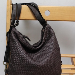 May include: A dark brown woven leather handbag with adjustable straps. The bag has a slouchy, casual look and is perfect for everyday use.