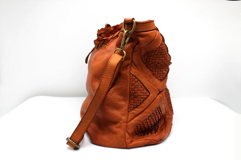 May include: A brown leather handbag with a braided strap and woven details.