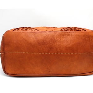 May include: The bottom of a brown leather tote bag with a woven design.