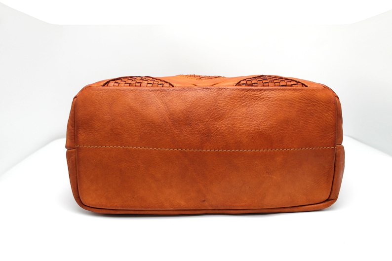 May include: The bottom of a brown leather tote bag with a woven design.