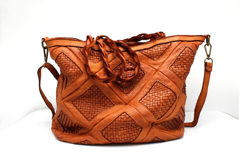May include: A large, brown leather tote bag with a woven pattern. The bag has a long strap and a top handle.