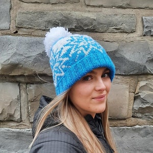 May include: A blue and white knit hat with a white pom pom. The hat has a snowflake pattern.