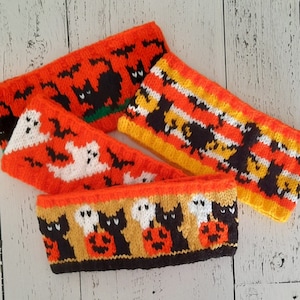 May include: Three knitted headbands with Halloween themes. The first headband features black cats and bats on an orange background. The second headband features white ghosts and bats on an orange background. The third headband features black cats, white ghosts, and orange pumpkins on a yellow background.