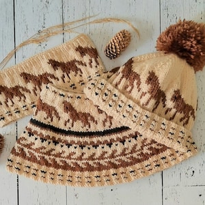 May include: A knitted hat and matching headband with a brown and white pattern of stylized animals. The hat has a brown pom-pom on top.